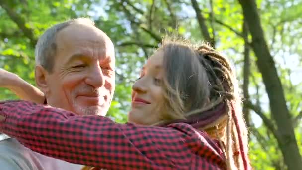 El padre mayor y la hija adulta se abrazan en el parque durante el día soleado. Concepto del día de los padres — Vídeo de stock