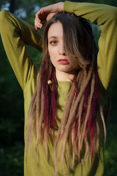 Draußen Porträt eines sinnlichen Mädchens mit langen Dreadlocks im grünen Hemd in einem Stadtpark bei Sonnenuntergang, seien andere, alternative Menschen Konzepte — Stockfoto