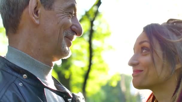 Ragazza moderna con dreadlocks sta abbracciando il suo padre anziano trascorrere del tempo insieme nel parco durante la giornata di sole. Concetto di giorno di padri — Video Stock