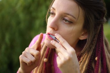 Açık havada, pembe örgü kazaklı, uzun rastalı genç bir kadının portresi geleneksel hutsul drymba, jaws harp, gümüş vargan.