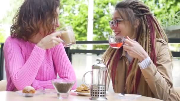 Two young female friends are having lunch break together in a coffee shop outdoors during a day in spring — Stock Video