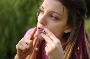 Açık havada, pembe örgü kazaklı, uzun rastalı genç bir kadının portresi geleneksel hutsul drymba, jaws harp, gümüş vargan.