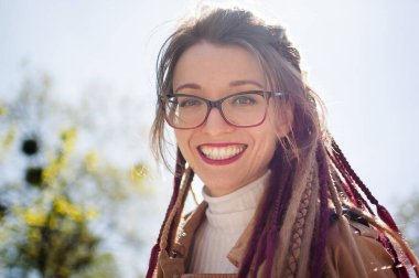 Uzun rastalı ve çıplak renkli siperlerde gözlüklü genç bir kız gökyüzünde büyüleyici bir gülümsemeyle kameraya bakıyor. Pozitif psikoloji kavramı