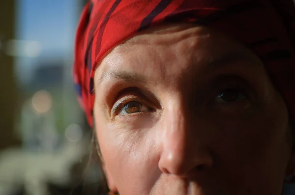 Közelkép női portré fáradt érett nő öltözött piros ruhába, és ül a nap végén a varrógép és a pamut bobbins háttér, szabó szakma koncepció — Stock Fotó