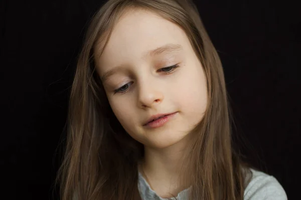 Retrato de una niña triste con el pelo largo y rubio y los ojos cerrados sobre fondo negro en el estudio —  Fotos de Stock