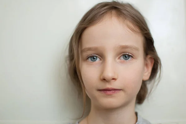 Retrato de una niña pequeña con el pelo largo y rubio y los ojos azules con cola de caballo está de pie sobre fondo blanco en el estudio —  Fotos de Stock