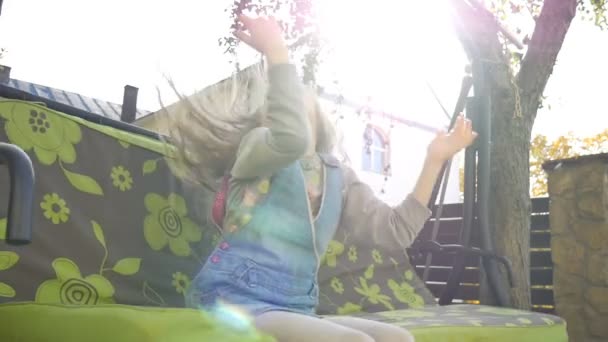 Niña pequeña rubia divirtiéndose en un columpio al aire libre durante el día soleado de verano en el patio de recreo en el jardín, concepto de infancia feliz — Vídeos de Stock