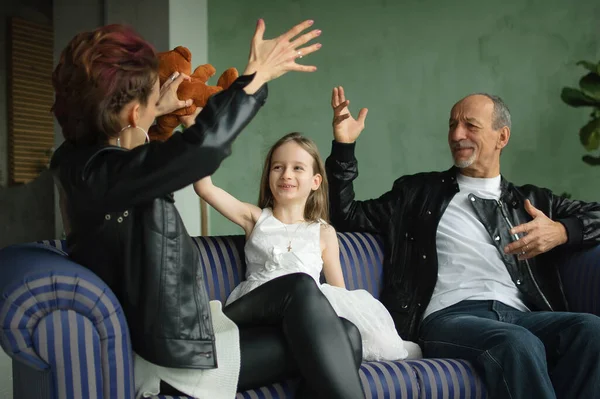 Retrato familiar de hija adulta, nieta pequeña y abuelo mayor en habitación loft con plantas de interior. Hombre y mujer están usando chaquetas de cuero negro en estilo punk, concepto de generación —  Fotos de Stock