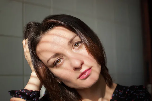 Feminino dentro de casa retrato de jovem morena com maquiagem e lábios sensuais em casa em azulejos brancos fundo na cozinha — Fotografia de Stock