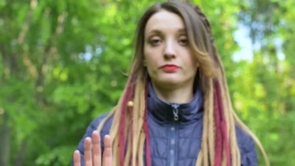 Modernes ernstes Mädchen mit langen Dreadlocks zeigt Hände mit dem geschriebenen Slogan Unsere Zukunft in deinen Händen auf grünem Baumhintergrund. Verantwortung, Klimaschutzkonzepte — Stockvideo
