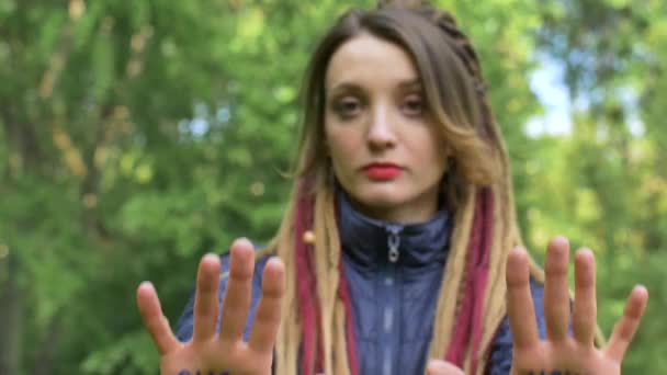 Nowoczesna poważna dziewczyna z długimi dredami pokazuje ręce z napisanym hasłem Nasza przyszłość w Twoich rękach na zielonym tle drzewa. Odpowiedzialność, koncepcje zmian klimatu — Wideo stockowe