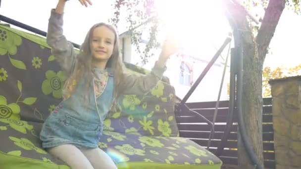 Menina loira criança se divertindo em um balanço ao ar livre durante o verão dia ensolarado no playground no jardim, conceito de infância feliz — Vídeo de Stock
