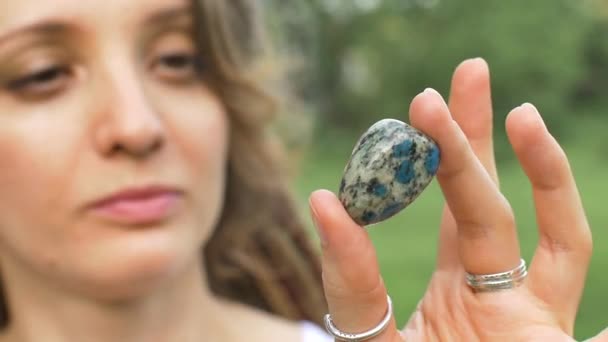 Junge schöne Mädchen mit Dreadlocks hält in der Hand Azurit, Naturstein draußen am Morgen in der Nähe ihres Gesichts mit perfekter Haut — Stockvideo