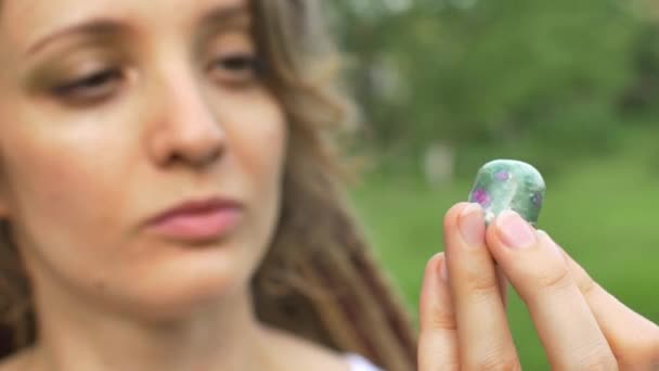 Retrato de uma menina com dreadlocks penteado segurando na mão pouca pedra natural anyolite — Vídeo de Stock