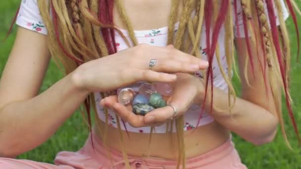 Dziewczyna z dredami fryzura gospodarstwa w ręku małe kamienie naturalne różane quarz, kryształ, aniolit, anyolit i azuryt, twarz nie jest widoczna — Wideo stockowe