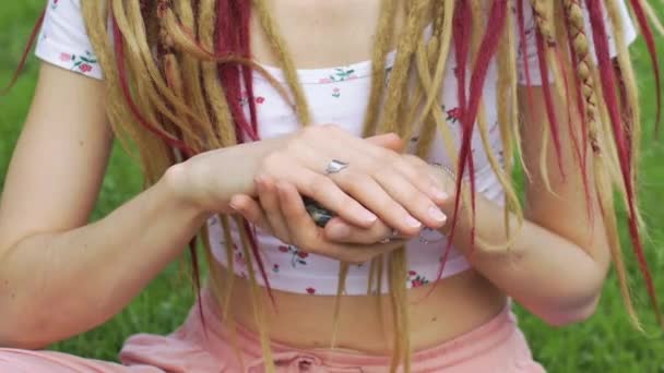 Chica con rastas peinado sosteniendo en la mano pequeñas piedras naturales rosa quarz, diamantes de imitación, angelita, anolita y azurita, la cara no es visible — Vídeo de stock