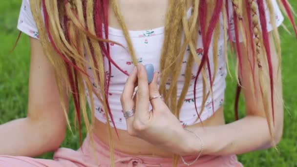 Ao ar livre retrato de uma menina com dreadlocks penteado segurando na mão pouco natural pedra azul angelite — Vídeo de Stock