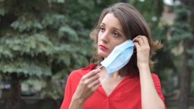 Pandemi sırasında virüsten korunmak için yüzüne cerrahi maske takan kırmızı gömlekli genç bir kadın. Coronavirus Covid-19 salgını, karantina konsepti
