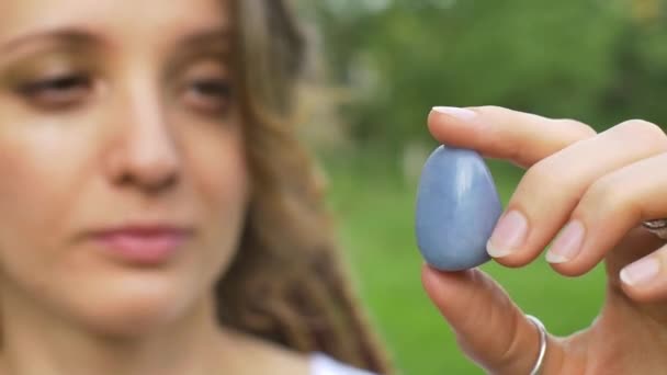 Potret luar ruangan seorang gadis dengan rambut gimbal memegang di tangan sedikit batu alami biru angelite — Stok Video