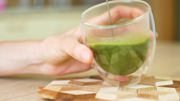 Kobiece ręce trzymając podwójne szkło z gorącą zieloną herbatą matcha latte i dodać więcej napojów do filiżanki. Detox i koncepcje zdrowego odżywiania — Wideo stockowe