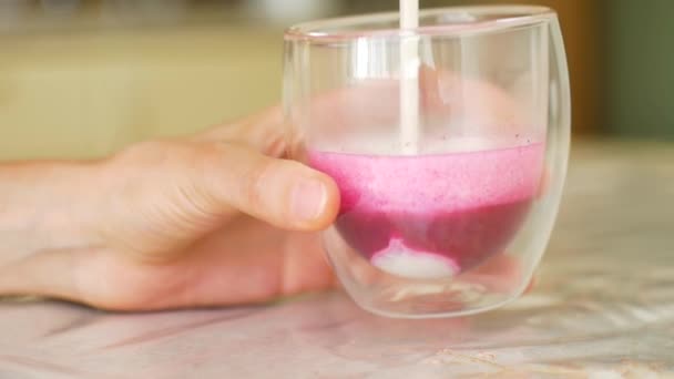 두 손을 잡고 뜨거운 분홍색 완두콩 라떼를 들고 그 컵에 음료를 더 붓는 여성들. 디톡스와 건강에 좋은 식사 개념 — 비디오
