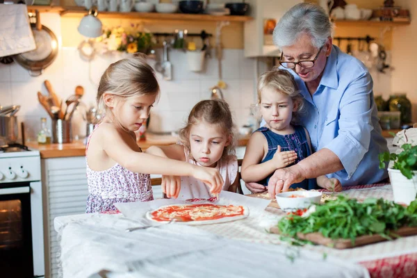 Kids and grandmother cooking italian pizza in cozy home kitchen for family dinner.