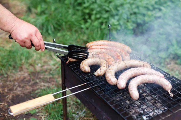 Man is cooking barbecue. Picnic with grilled sausage. Bbq party in summer garden.