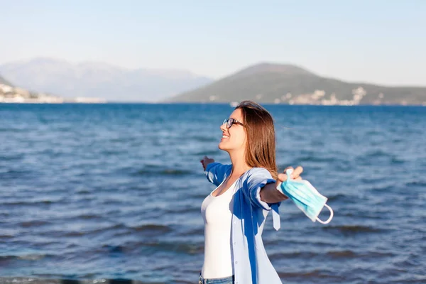 Corona free country. Happy woman breathing fresh air without mask at sea beach outdoors. Coronavirus quarantine finish