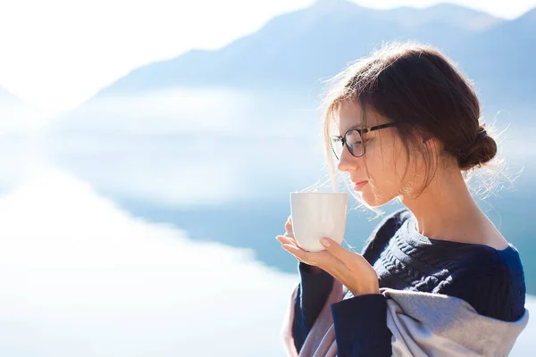 Woman drinking coffee at sea beach. Cozy winter picnic. Girl enjoying morning tea, life, travel, relaxation.