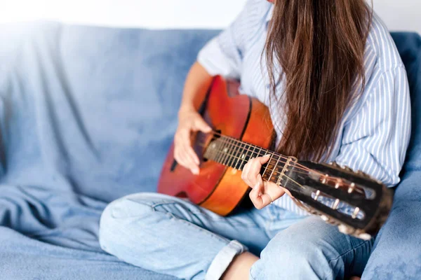Young woman playing guitar at home. Happy girl enjoying music. Female musician in living room.
