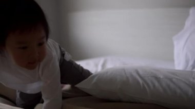 Asyalı Çinli Toddler ebeveyn için bakmak için yataktan tırmanıyor 