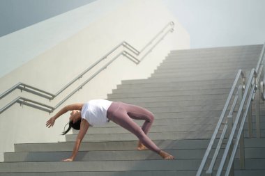 Halka açık yerlerde yoga yapma eğilimini takiben, Asyalı Çinli kadın merdivenlerde yoga yapıyor.