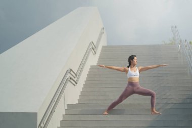 Halka açık yerlerde yoga yapma eğilimini takiben, Asyalı Çinli kadın merdivenlerde yoga yapıyor.