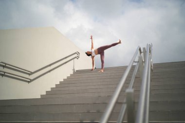 Halka açık yerlerde yoga yapma eğilimini takiben, Asyalı Çinli kadın merdivenlerde yoga yapıyor.