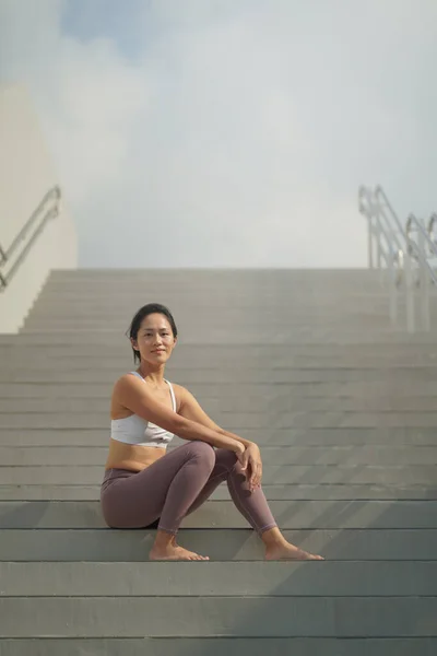 アジア系中国人女性がスポーツ服装で階段で休んでいる — ストック写真
