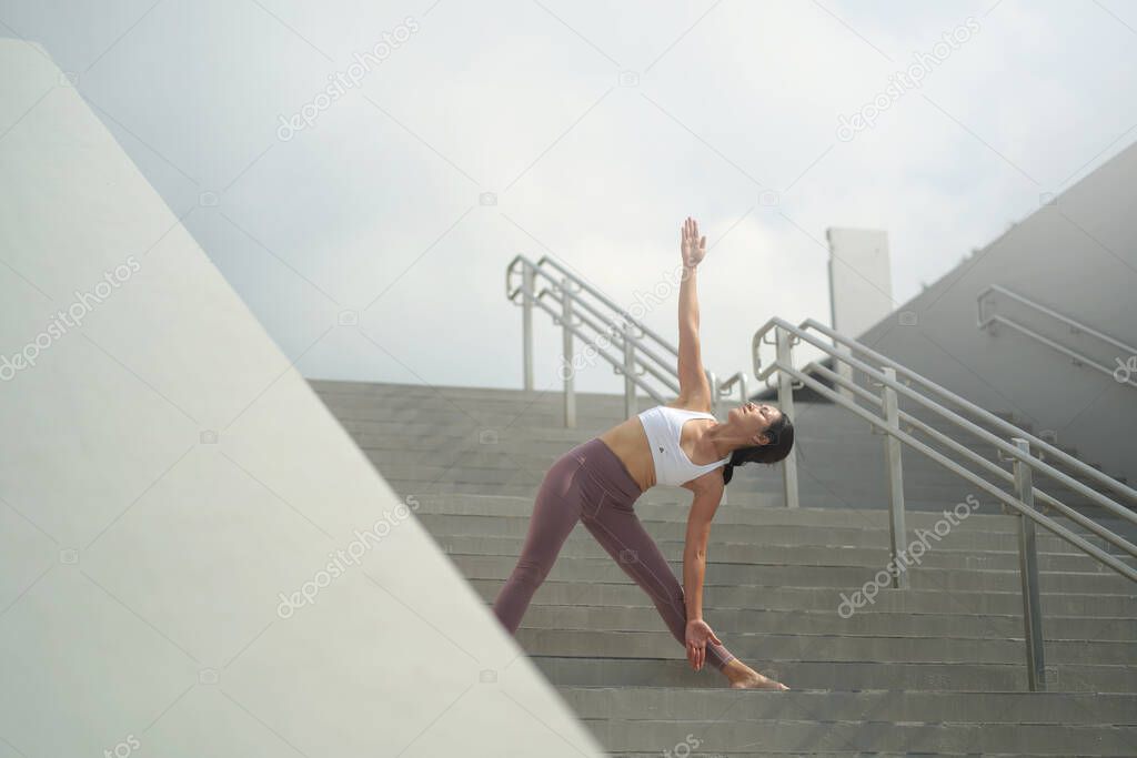 following the trend of doing yoga in public open spaces, asian chinese lady doing Yoga on stairs