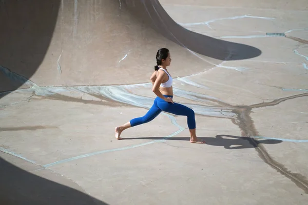 Following the trend of doing yoga in public spaces, Asian Chinese Woman does Yoga in public skate park