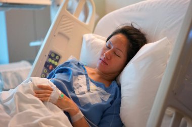 Asian Chinese Woman patient lying in the hospital bed asleep clipart