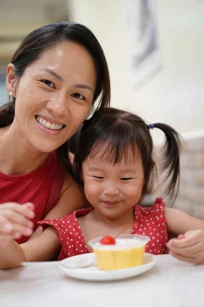 Happy Asian chinese mother and daughter enjoying a bowl of dessert