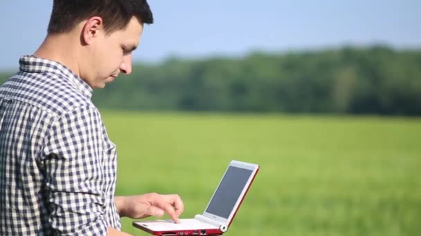 Fermierul caucazian brunet de pe teren lucrează cu un laptop. Oamenii de știință care lucrează în domeniu cu tehnologie agricolă . — Videoclip de stoc