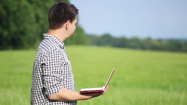 Der kaukasische, brünette Bauer auf dem Feld arbeitet mit einem Laptop. Wissenschaftler, die im Feld mit Landtechnik arbeiten. — Stockvideo