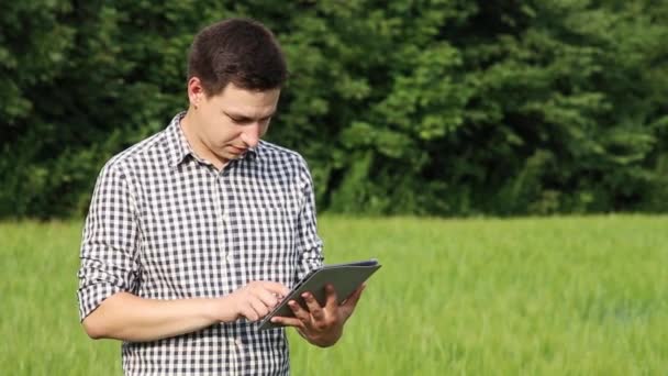 Der kaukasische, brünette Bauer auf dem Feld arbeitet mit einem Tablet. Wissenschaftler, die im Feld mit Landtechnik arbeiten. — Stockvideo