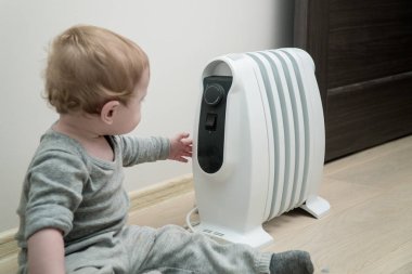 Elektrikli yağ ısıtıcı yakın katta oturan küçük çocuk