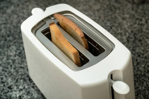 Tostadora blanca con pan tostado para el desayuno en el interior. Mesa gris — Foto de Stock