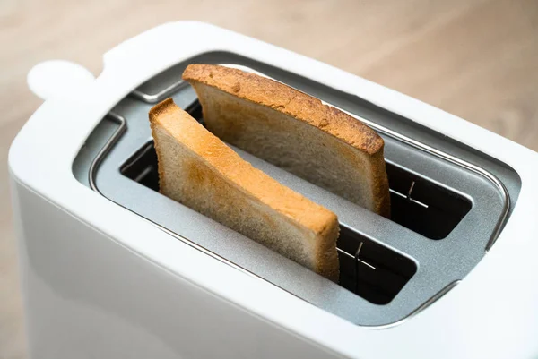 Tostadora blanca con pan tostado para el desayuno en el interior. Fondo de madera — Foto de Stock