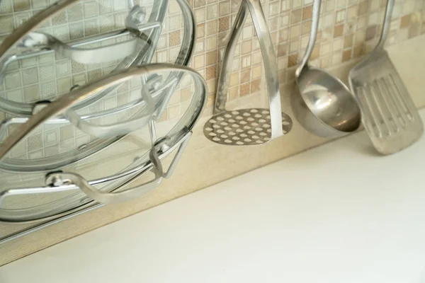 Tampas de vidro para vasos e utensílios de cozinha na parede acima da mesa — Fotografia de Stock