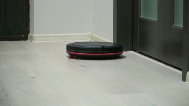 Aspirador robótico no piso de madeira laminado. Tecnologia de limpeza inteligente. Aspirador de pó de limpeza do apartamento — Vídeo de Stock