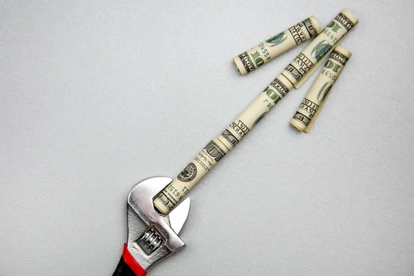 Para birimi para ve araçları sabitleme kavramı. İngiliz anahtarı ve gri arka plan üzerinde dolar. Para bir oktur