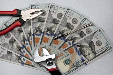 Para birimi para ve araçları sabitleme kavramı. İngiliz anahtarı, pense, tornavida ve gri arka plan üzerinde dolar