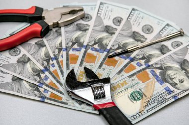 Para birimi para ve araçları sabitleme kavramı. İngiliz anahtarı, pense, tornavida ve gri arka plan üzerinde dolar
